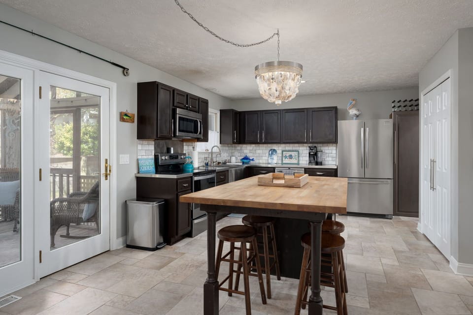 Step into your fully equipped kitchen featuring modern appliances, spacious counters, and a charming butcher block island perfect for cooking together.