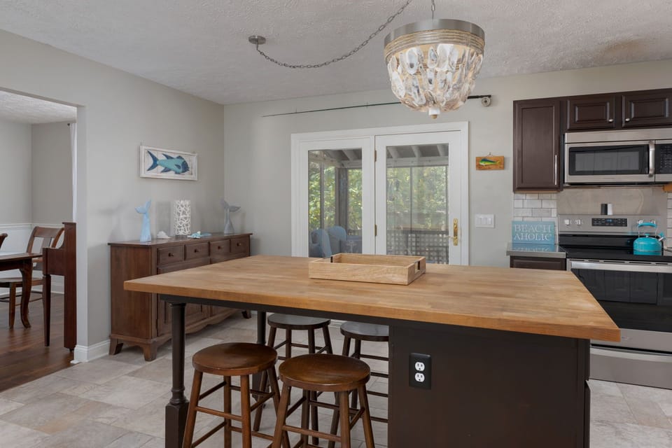 Your open kitchen invites shared meals with its warm wood island, coastal touches, and French doors leading to your private outdoor space.