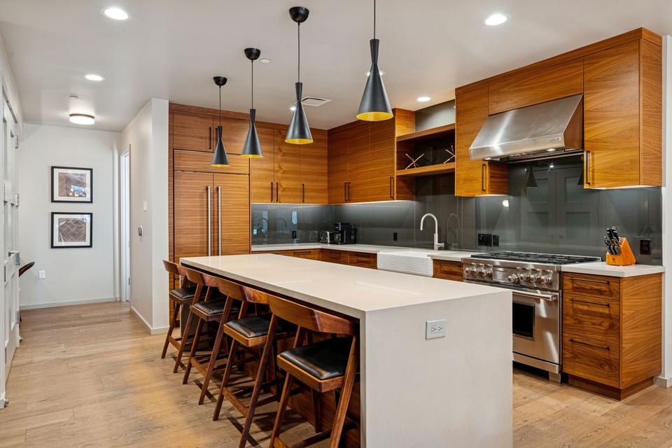Gourmet kitchen with double island, custom cabinetry, and industrial lighting