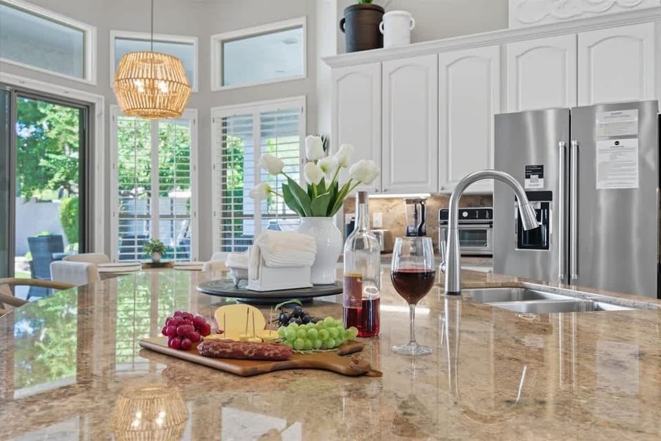 The kitchen showcases granite countertops, crisp white cabinets, stainless steel appliances, and a spacious island with breakfast bar seating for three.