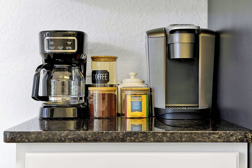 coffee and tea station with drip and single-serve coffee makers on a granite countertop