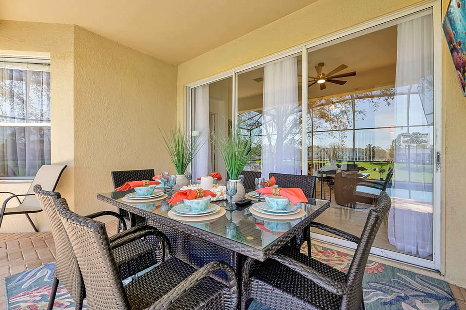 Covered patio dining area with wicker furniture and a view of the green lawn.