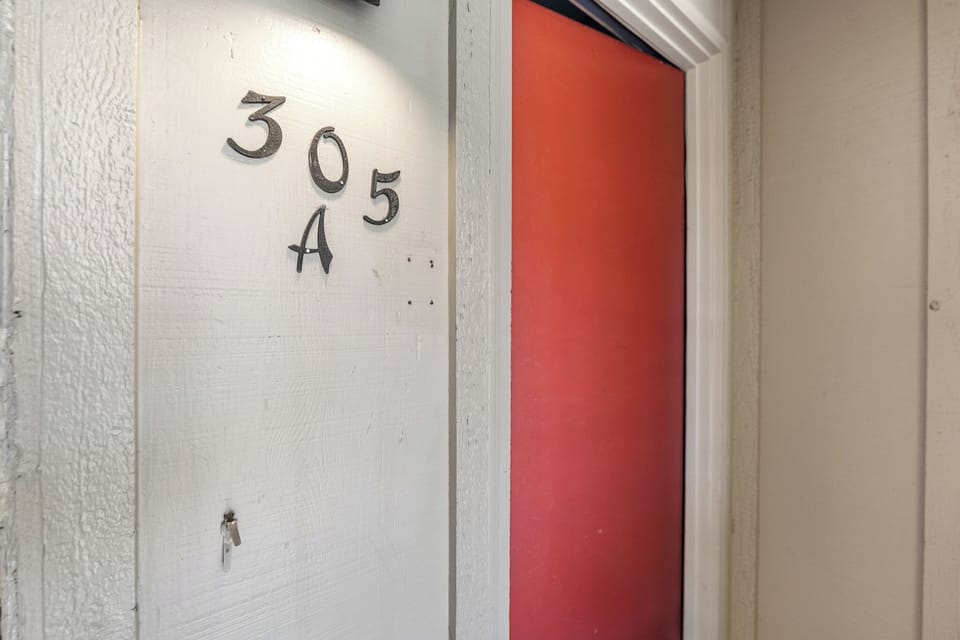 Your welcoming door to apartment 305A awaits, with a warm coral accent that hints at the cozy retreat inside.