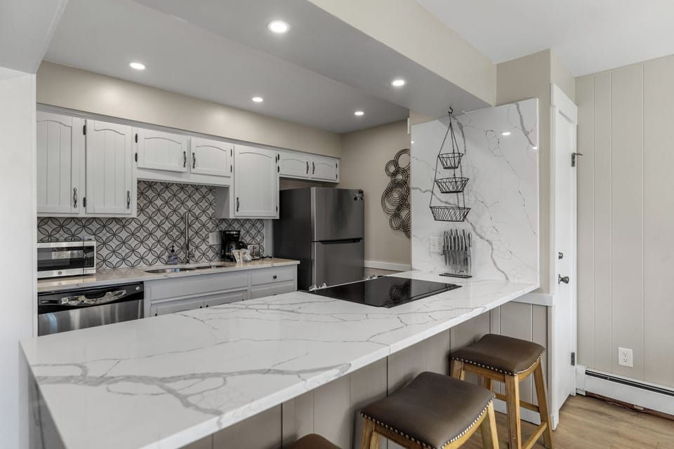 Your fully equipped kitchen features marble countertops, modern appliances, and stylish seating—perfect for preparing meals and morning coffee.