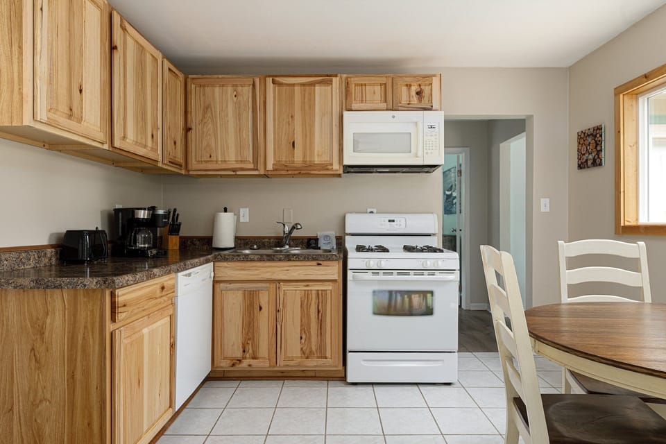 Bright kitchen w/ wood cabinets, full-size appliances & dining space nearby