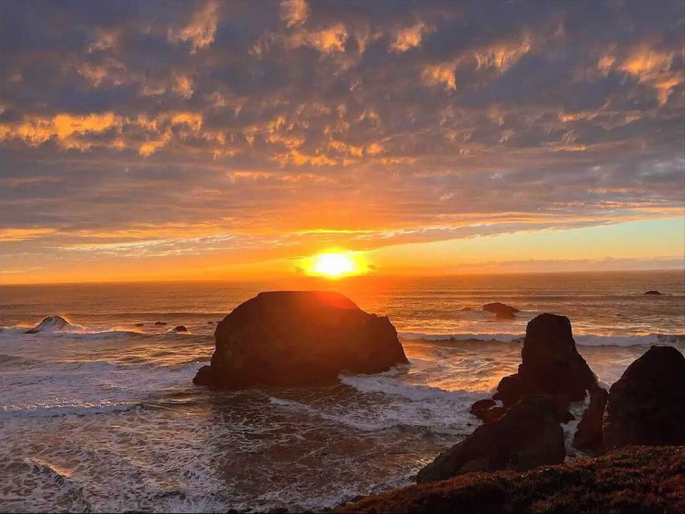 End your day with a colorful ocean sunset right outside your door. The sky glows over rugged coastal rocks, creating a peaceful and unforgettable backdrop.