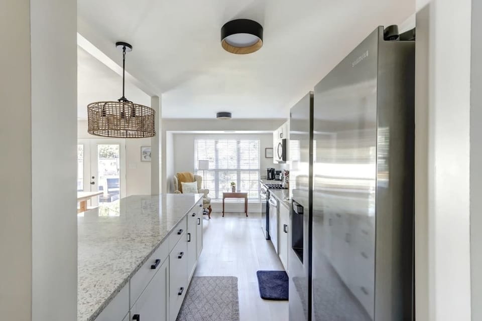 An elongated layout with sleek white cabinets and modern appliances make meal prep and cooking easy as pie.
