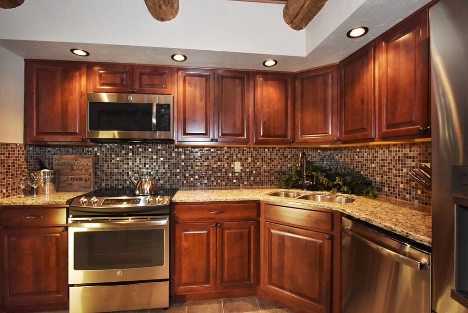 Fully equipped kitchen with rich wooden cabinetry and modern appliances, perfect for preparing meals with ease.