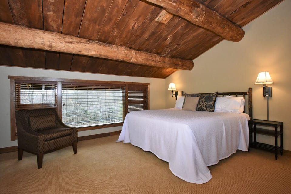 Serene bedroom under rustic wooden beams, offering a tranquil and cozy atmosphere for relaxation.