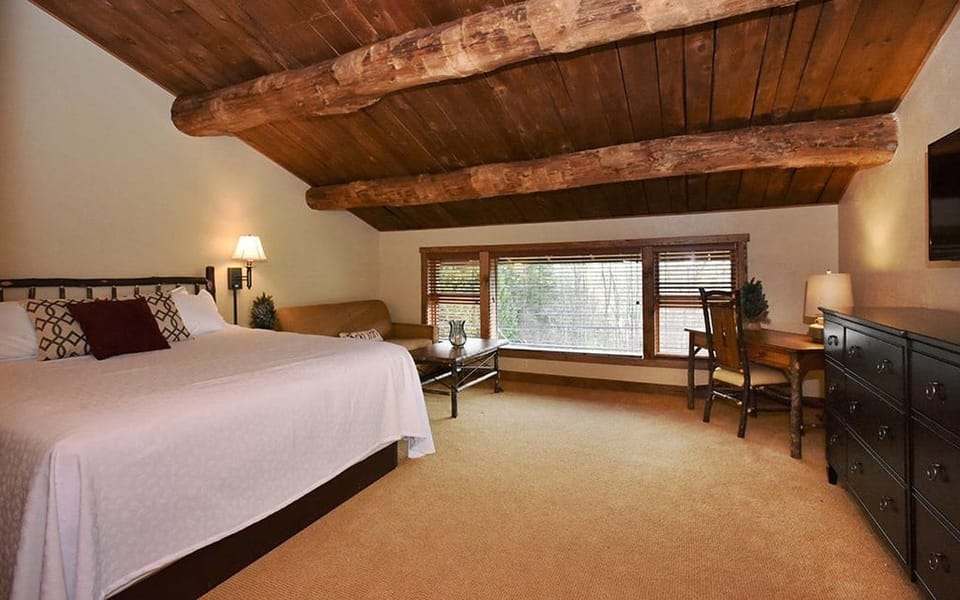 Spacious bedroom with rustic wooden beams and cozy furnishings, perfect for a restful night.