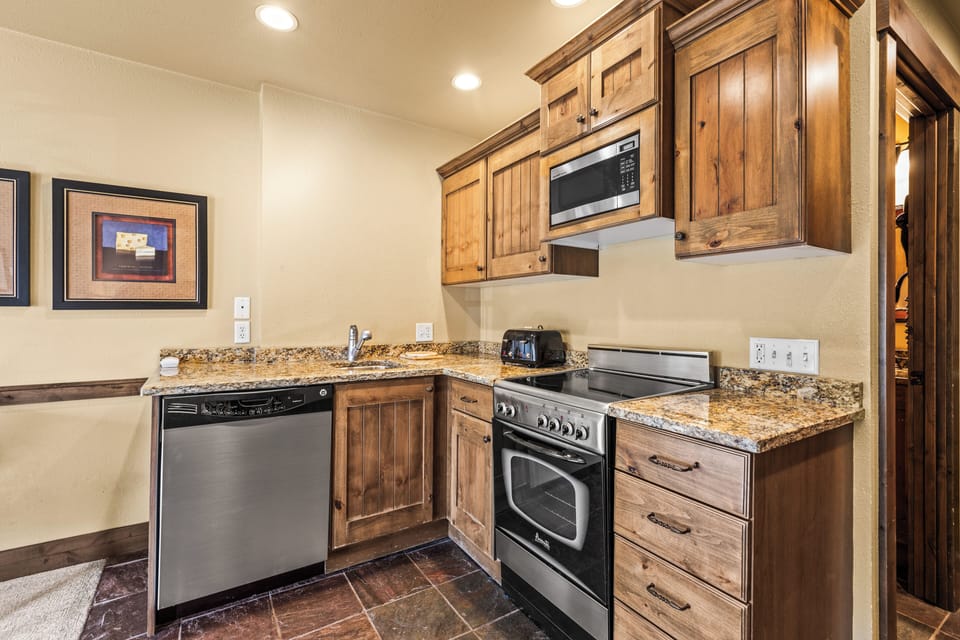 The efficient kitchen with oven, refrigerator, microwave, and dishwasher.