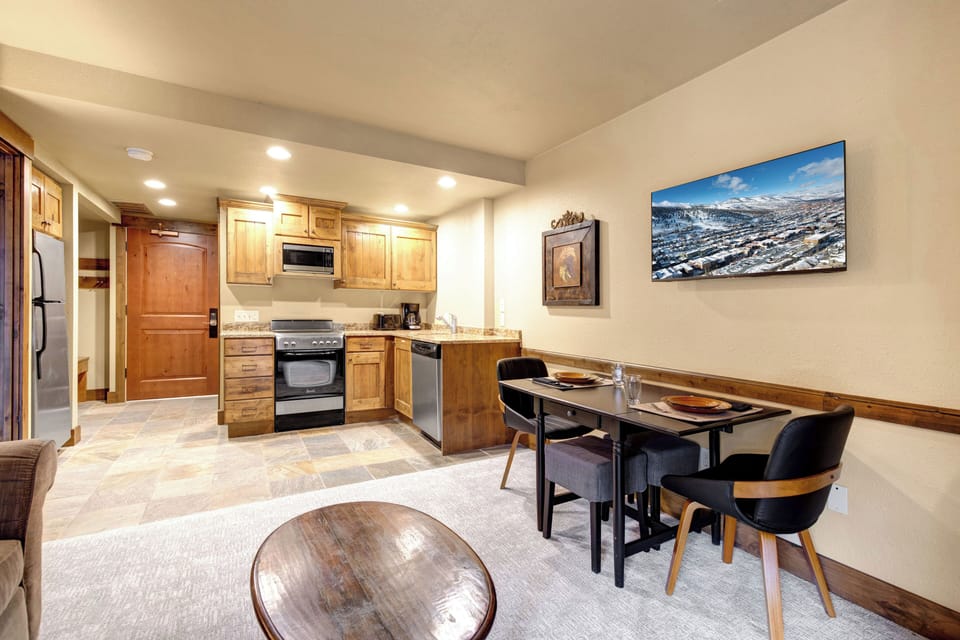 Your cozy open-concept space combines a fully equipped kitchen with warm wood cabinets and a stylish dining area.