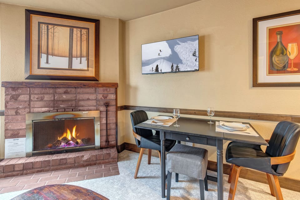 A dining table for two next to a cozy fireplace.