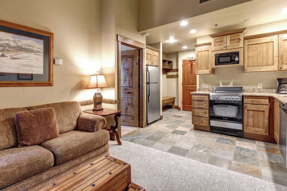 The open-plan living space flows seamlessly from plush seating to a fully equipped kitchen.