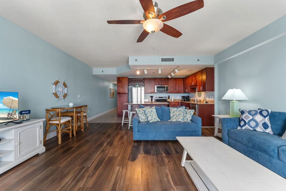 Inviting Coastal Decor: Stylish and comfortable living area with a queen-size sleeper sofa, beach-inspired accents, and warm wood flooring.