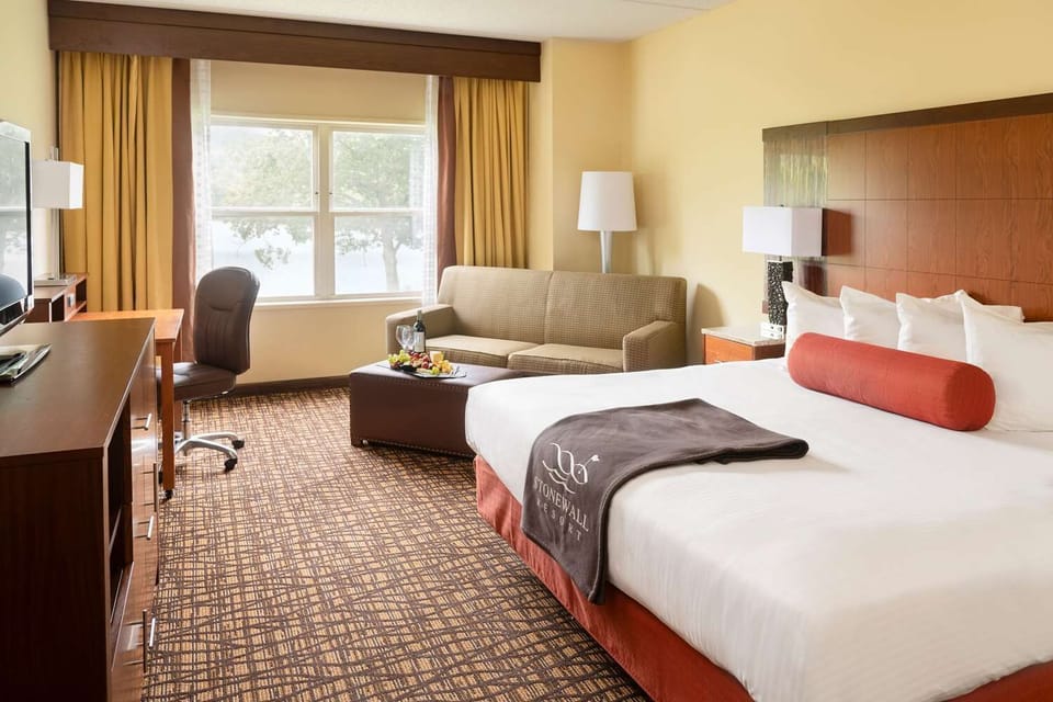 Plush bedding, warm tones, and natural light come together in a cozy retreat with serene park views.