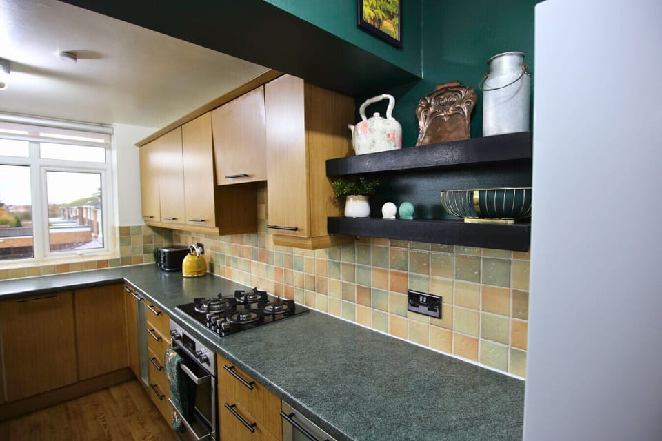 Kitchen hob area with open shelving and tiled splashback