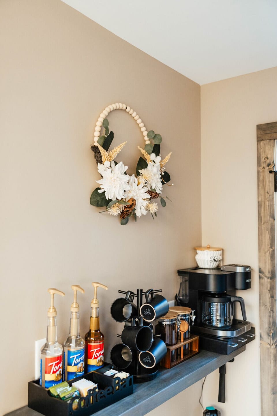 Cozy coffee bar with a drip coffee maker, syrups, and mugs—perfect for your morning brew.