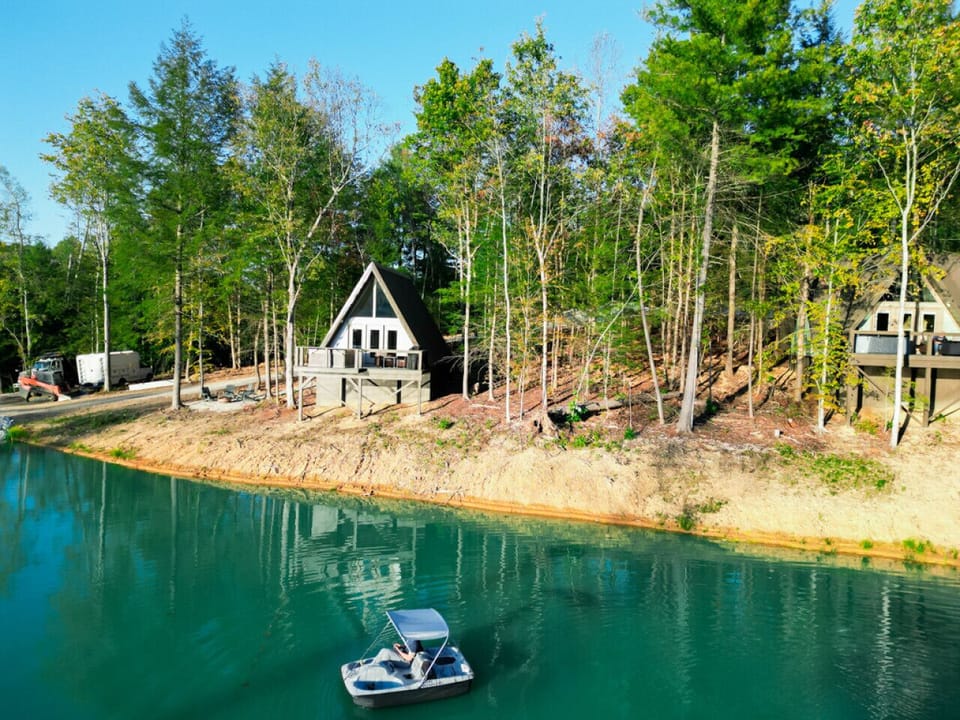 Private A-frame cabin overlooking a peaceful pond, surrounded by trees with a spacious deck for relaxing views.
