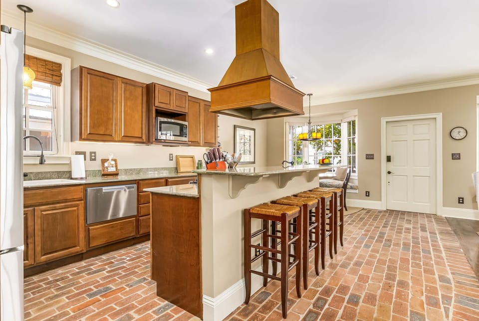 Gourmet kitchen with gas range, copper hood, granite counters, and Chicago brick floors