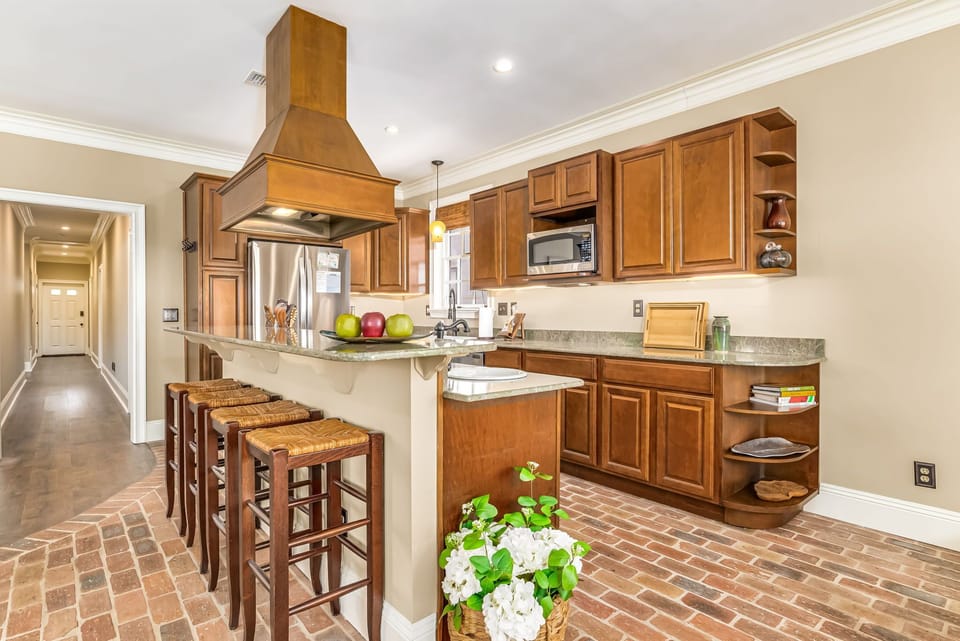 Gourmet kitchen with gas range, copper hood, granite counters, and Chicago brick floors