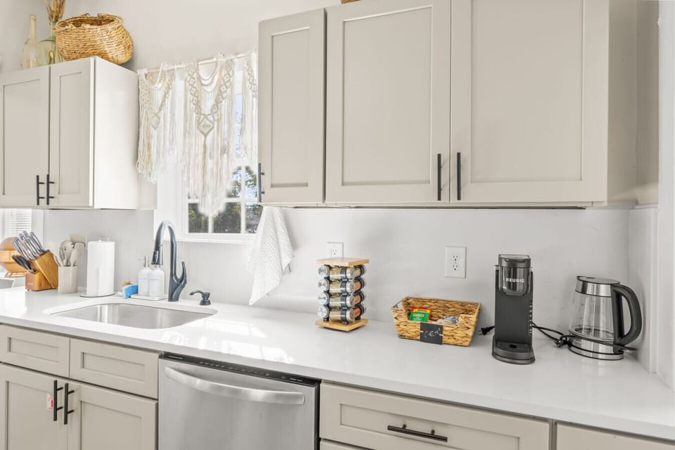 Streamlined kitchen counter w/ modern cabinetry, coffee setup, & everyday essentials close at hand.