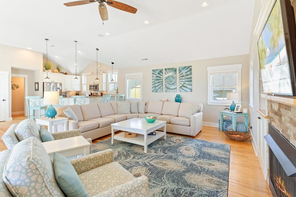 Bright and inviting living area with plush seating, large flat-screen TV, surround sound, and access to the oceanview deck.