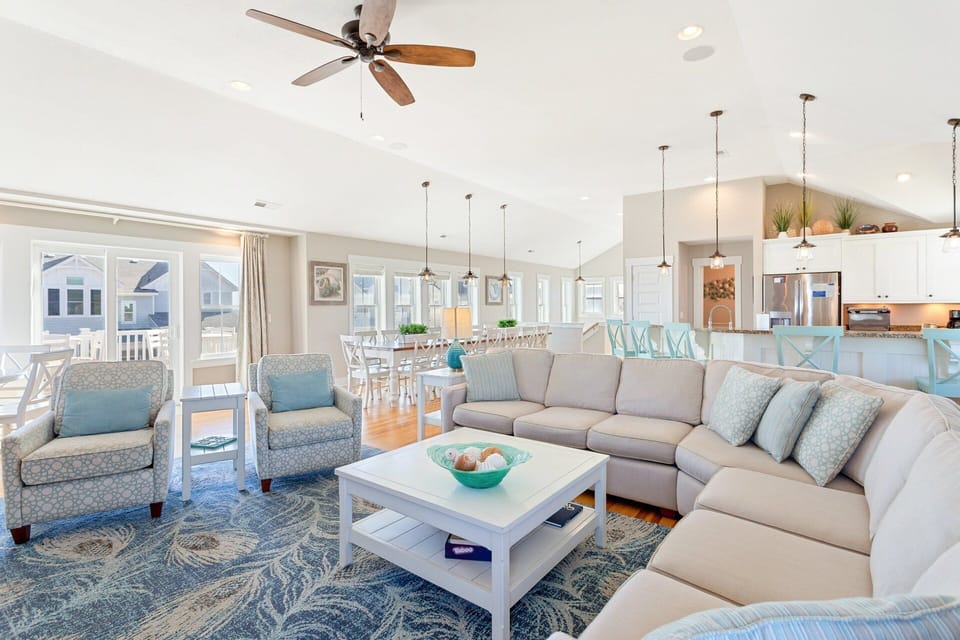 Bright and inviting living area with plush seating, large flat-screen TV, surround sound, and access to the oceanview deck.