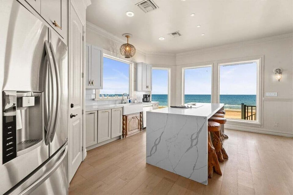 Bathed in natural light, the gourmet kitchen dazzles with panoramic Gulf views, bespoke cabinetry, and a waterfall-edge island that redefines coastal elegance.