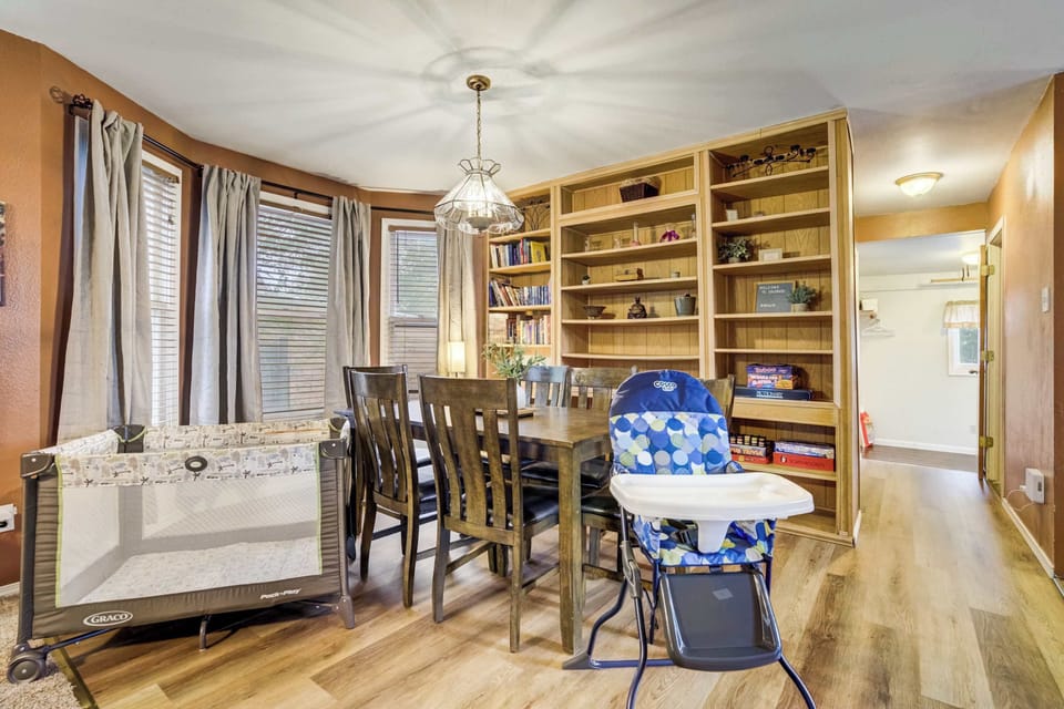 The dining space features warm tones, built-in shelving, and a family-friendly setup. A high chair and pack-n-play make it perfect for guests traveling with little ones.