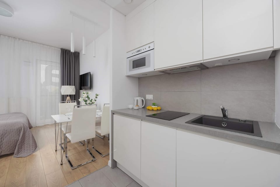 The fully equipped kitchenette in bright tones blends seamlessly with the studio’s décor, creating a cohesive and stylish look.