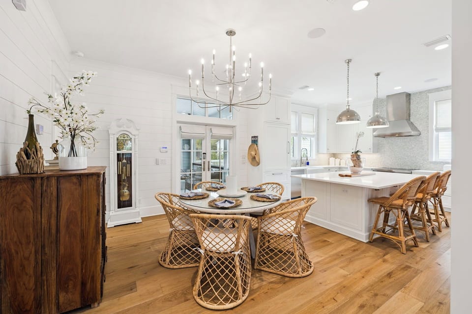 You'll love cooking and dining in this stunning open kitchen with gleaming white counters, elegant chandelier, and natural rattan seating that creates the perfect gathering space.