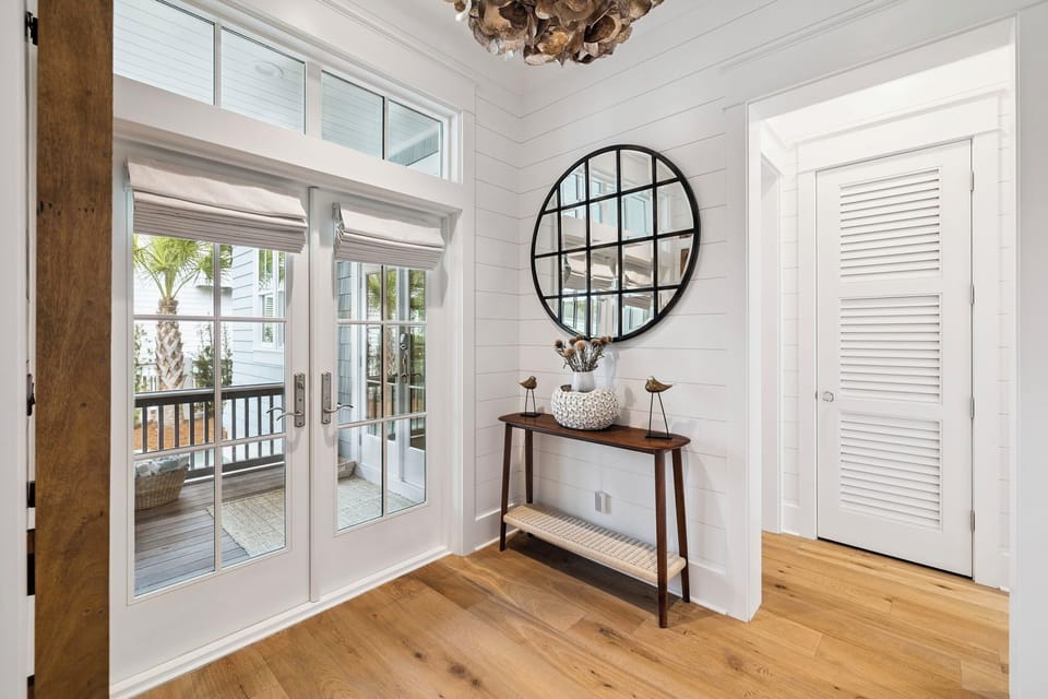 Step into your bright coastal entryway, where natural light floods through French doors leading to your private balcony with palm tree views.