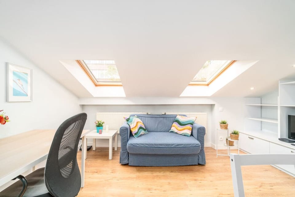 Bright Living Area with Sofa, TV, and Working Desk under Skylights | Book Now with RENTUJEMY.COM