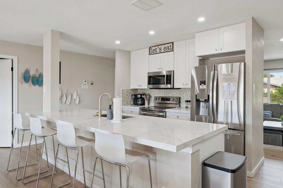 Bright open kitchen with island seating, stainless appliances, and modern style.