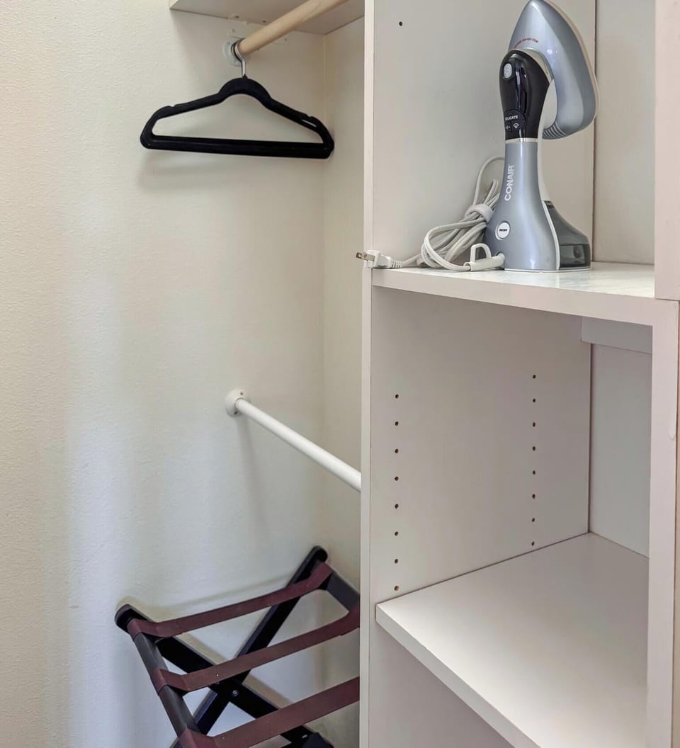 Guest-ready closet with hangers, steamer, shelves, and luggage rack