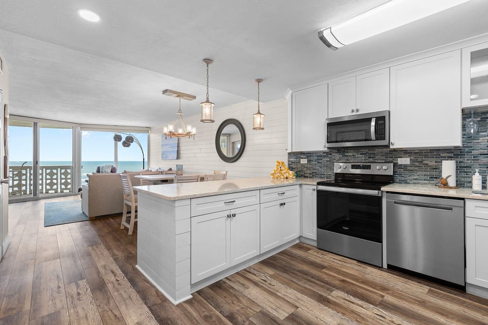 Bright beachfront condo with a modern kitchen, ocean views, and open dining space. Enjoy seaside serenity with stainless appliances, coastal décor, and steps from the shore — your perfect beach stay awaits!