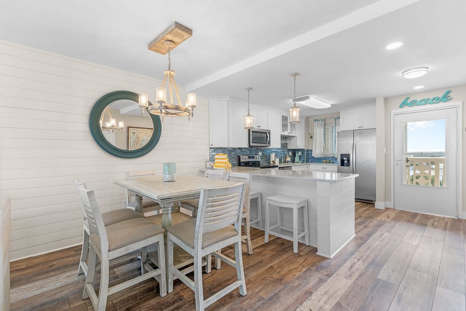 Enjoy coastal charm in this bright beachside kitchen and dining space featuring modern appliances, ocean hues, and inviting décor—perfect for gathering after a day by the shore.