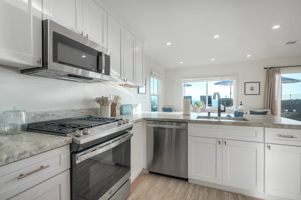 Modern kitchen with ocean views and sunlight.