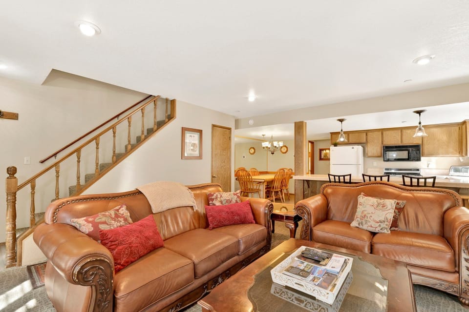 Cozy mountain living room with a stone fireplace, comfy seating, and smart TV—perfect for relaxing evenings, movie nights, and warm cabin vibes after outdoor adventures.
