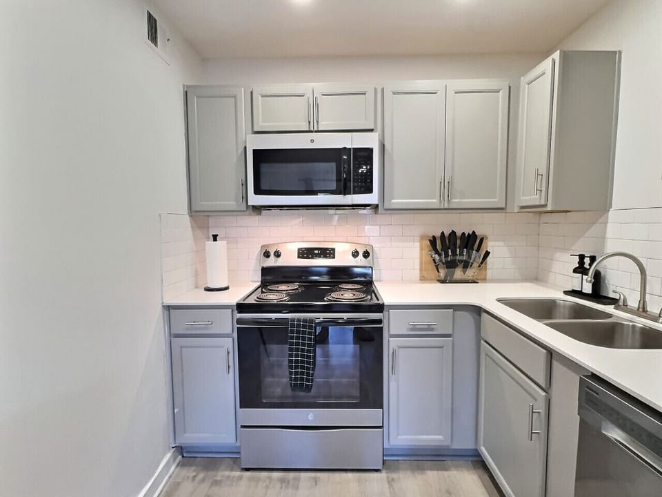 Modern kitchen with sleek stainless steel appliances and neatly arranged utensils, perfect for effortless cooking during your short-term rental stay.