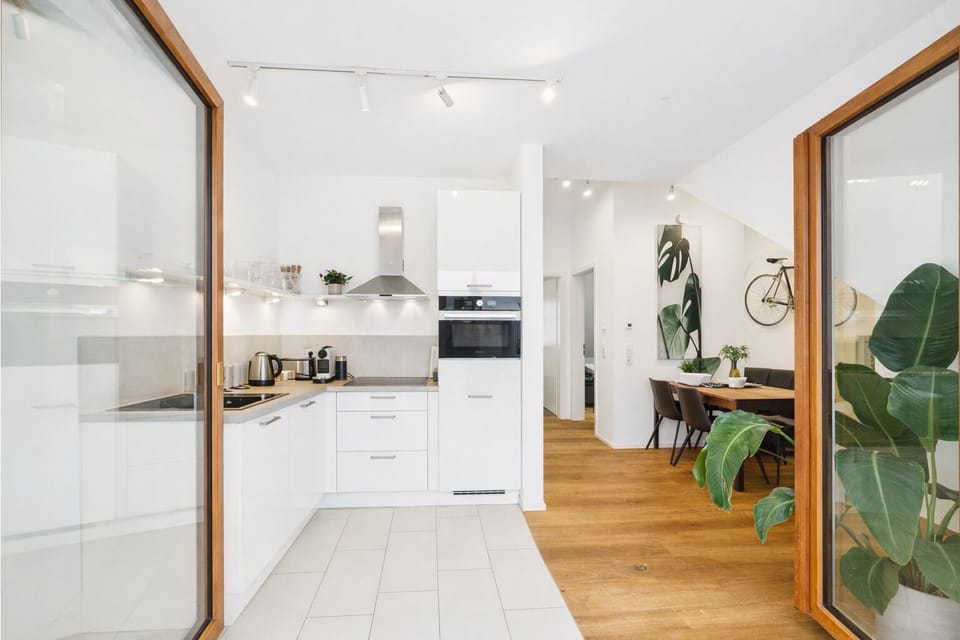 Modern, fully equipped kitchen in a bright design with an oven, cooktop, and coffee machine.