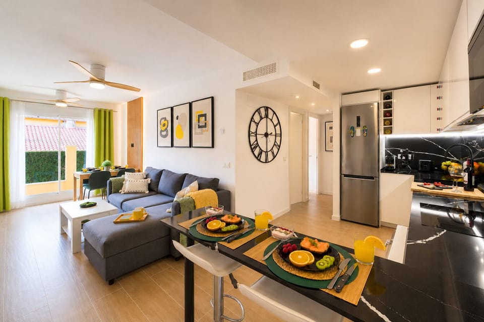 Stylish open-plan living room with a modern kitchen, smart TV, and natural light throughout — ideal for relaxing or sharing a glass of wine after a day by the beach.