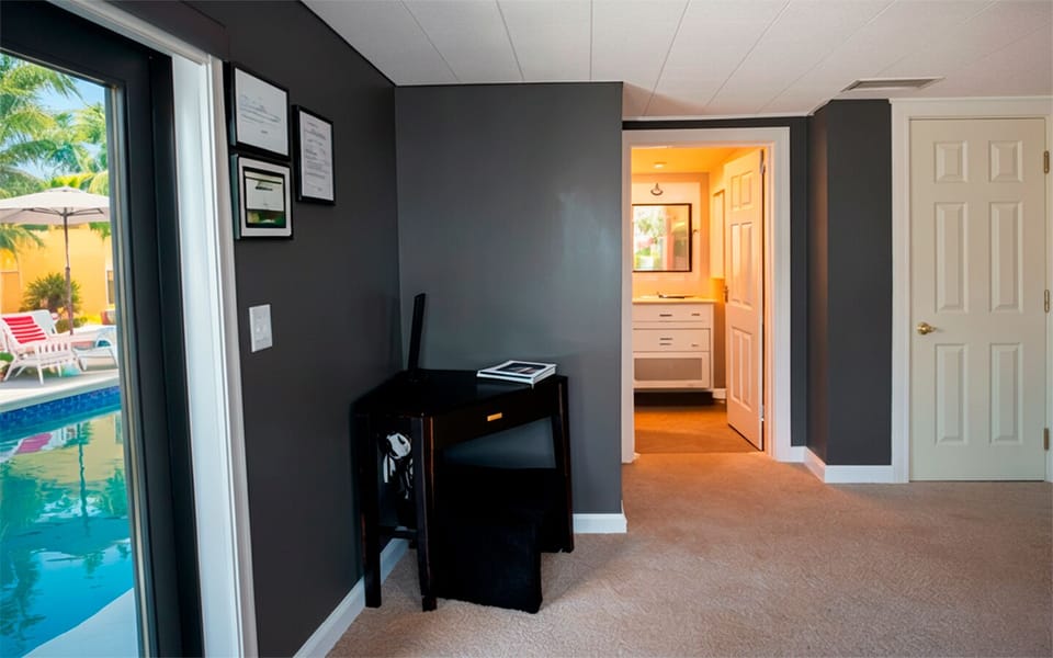Functional interior view of The Red Room, featuring a dedicated desk, direct pool access, and a private bathroom entry.