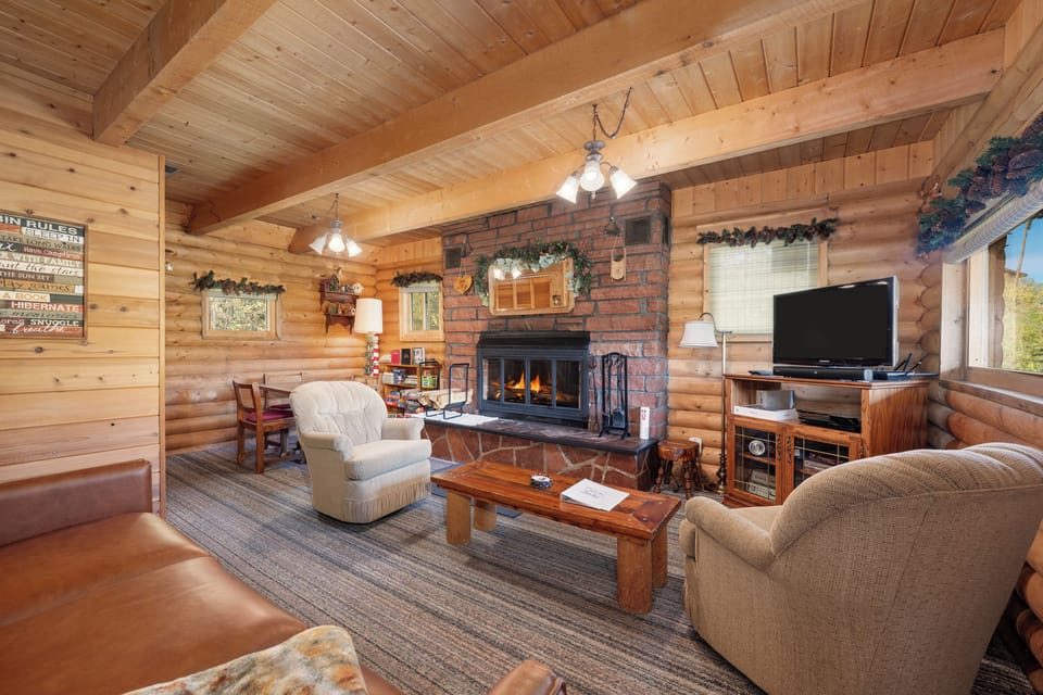 Unwind by your cozy brick fireplace in this rustic log cabin living room, where warm wood beams frame your perfect mountain retreat.