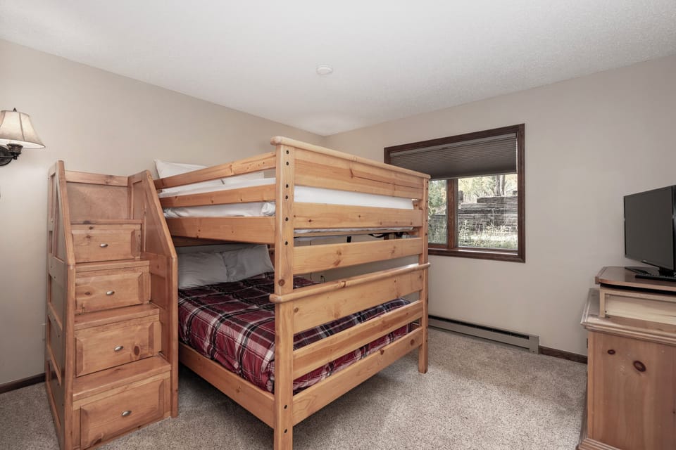 Your kids will love this cozy bedroom with sturdy wooden bunk beds and built-in storage stairs, plus their own TV for movie nights.