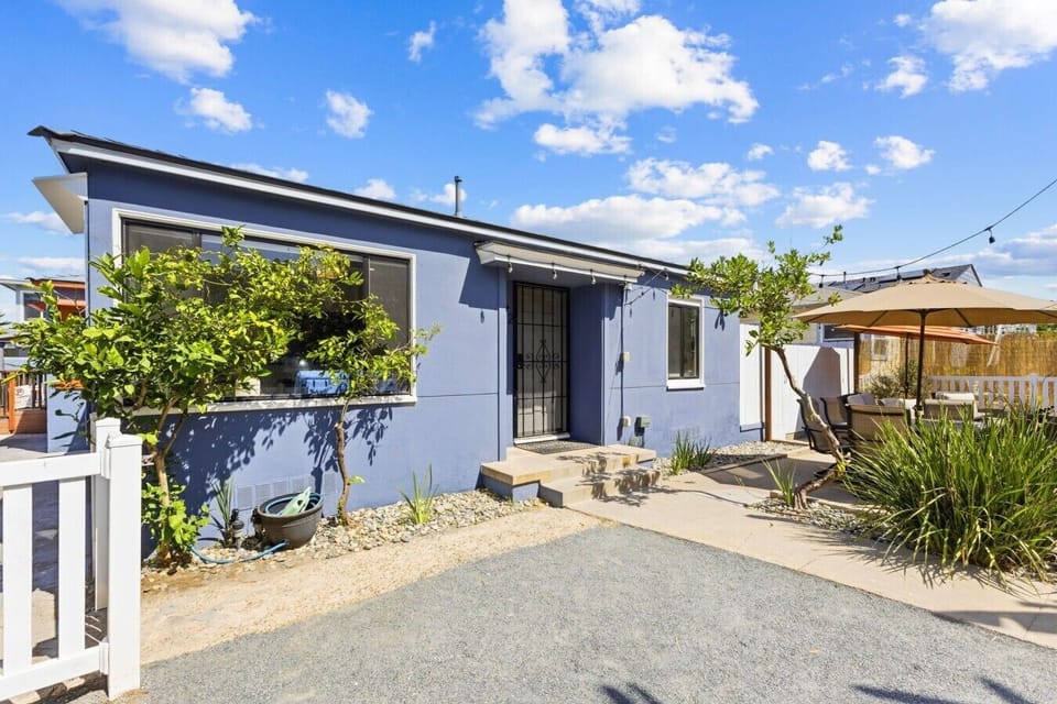 Exterior front view of the home featuring charming blue siding, gated entrance, and private patio access.