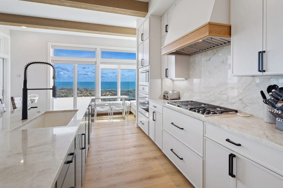 The fully equipped kitchen boasts a 6-burner stove, double ovens, large pantry, and sleek bar seating for four.