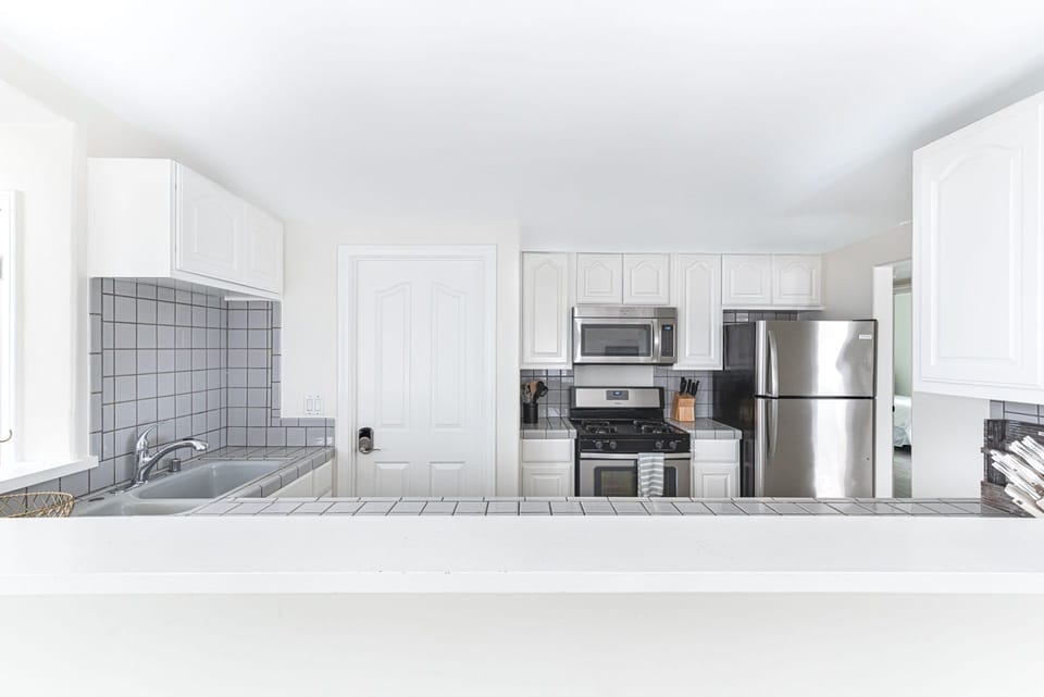 Spacious main floor galley kitchen with crisp white cabinetry and modern finishes
                