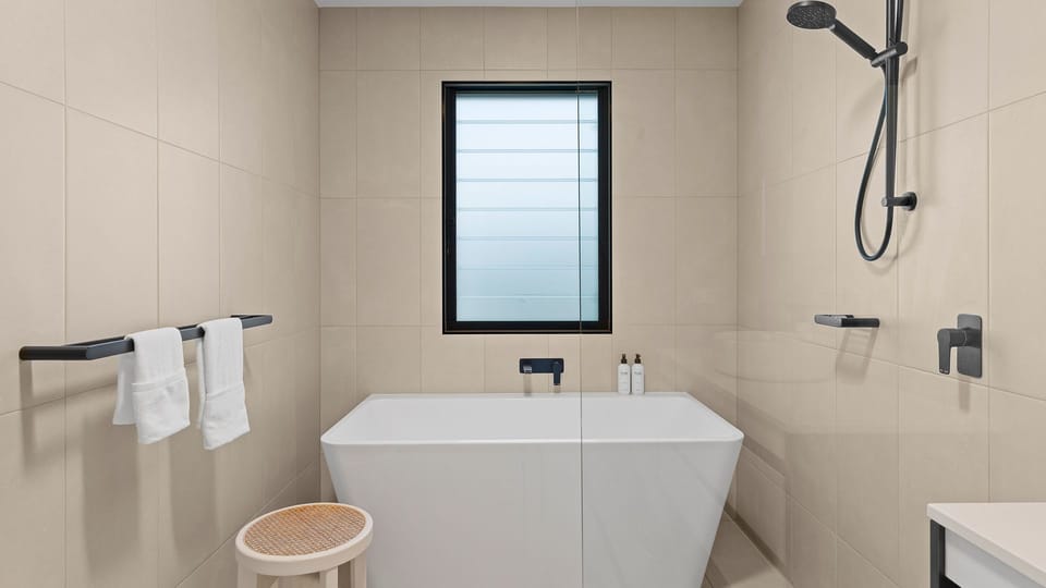 Clean and contemporary bathroom with a white soaking tub and overhead shower.   